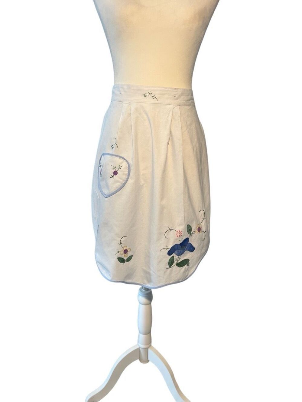 White cotton apron with embroidered flowers, pocket and light blue trim